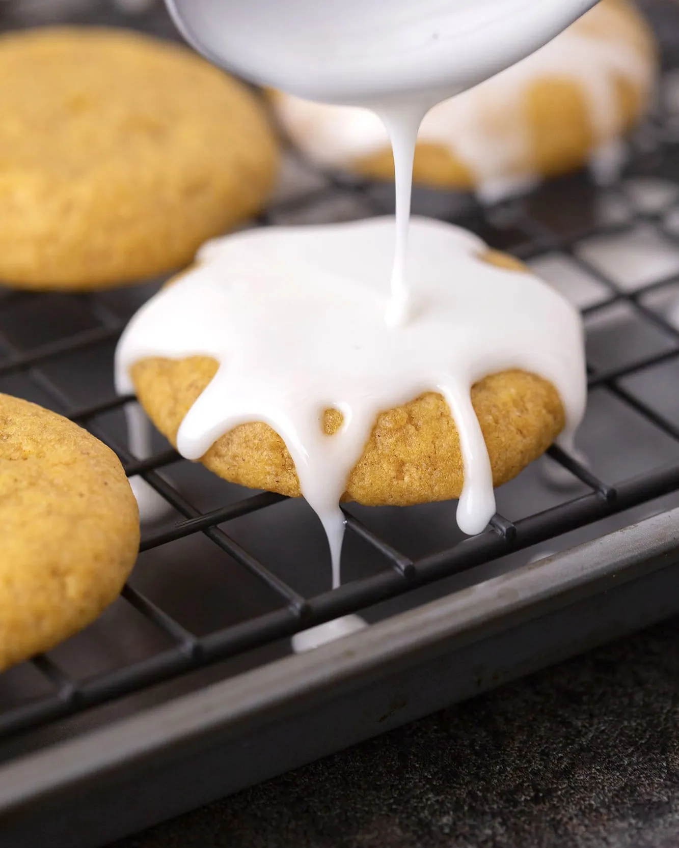 A home baker mixing smooth powdered sugar icing in a small ceramic bowl.