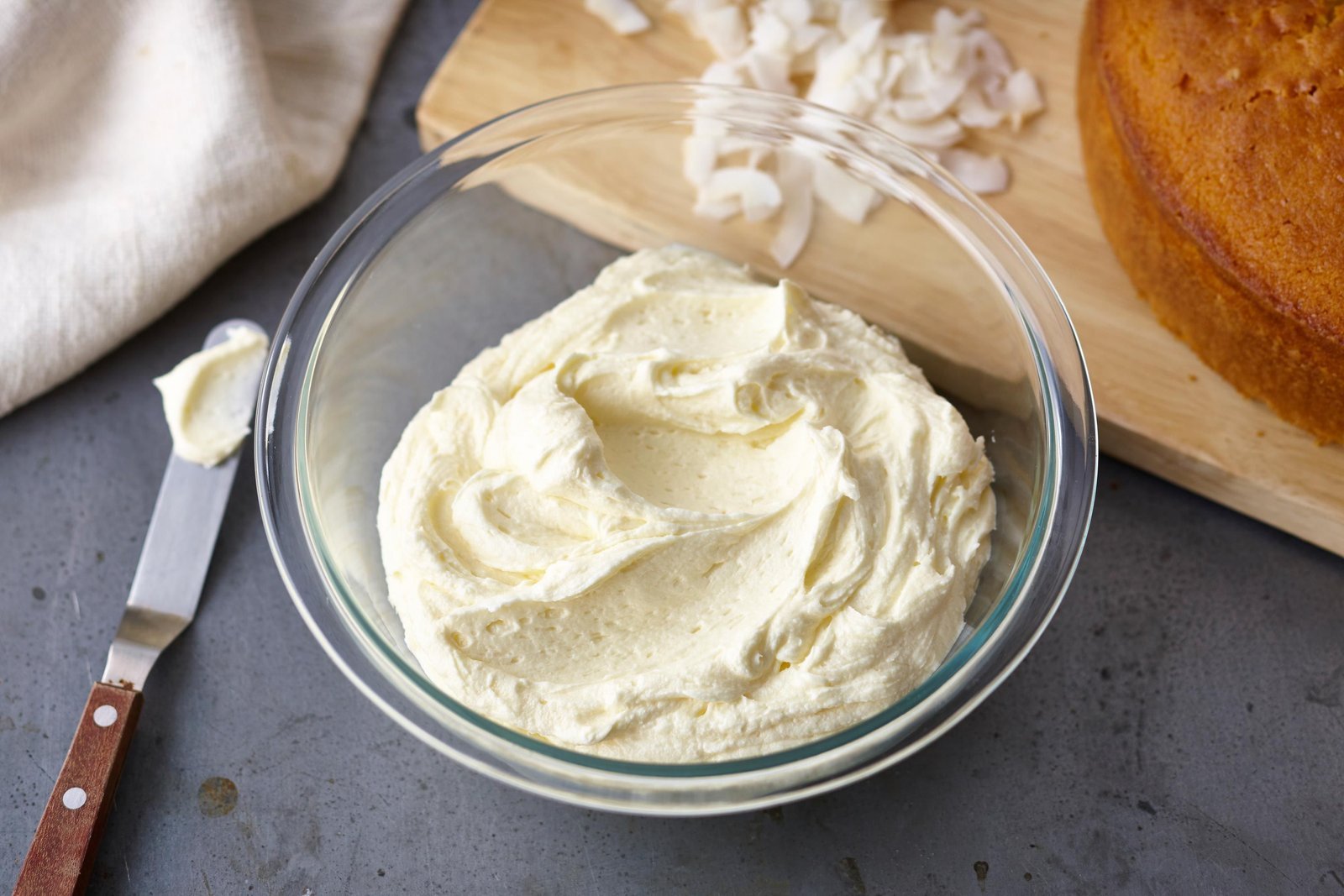 A home baker prepares homemade butter icing using a hand mixer.
