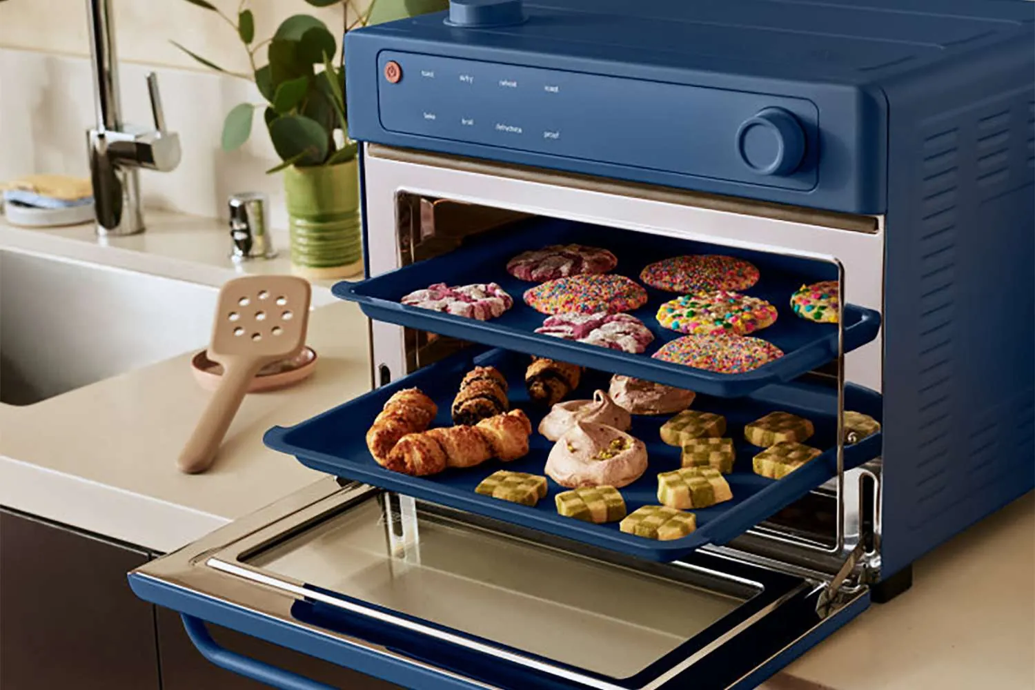 Hand adjusting Wonder Oven dial beside manual and chicken wings