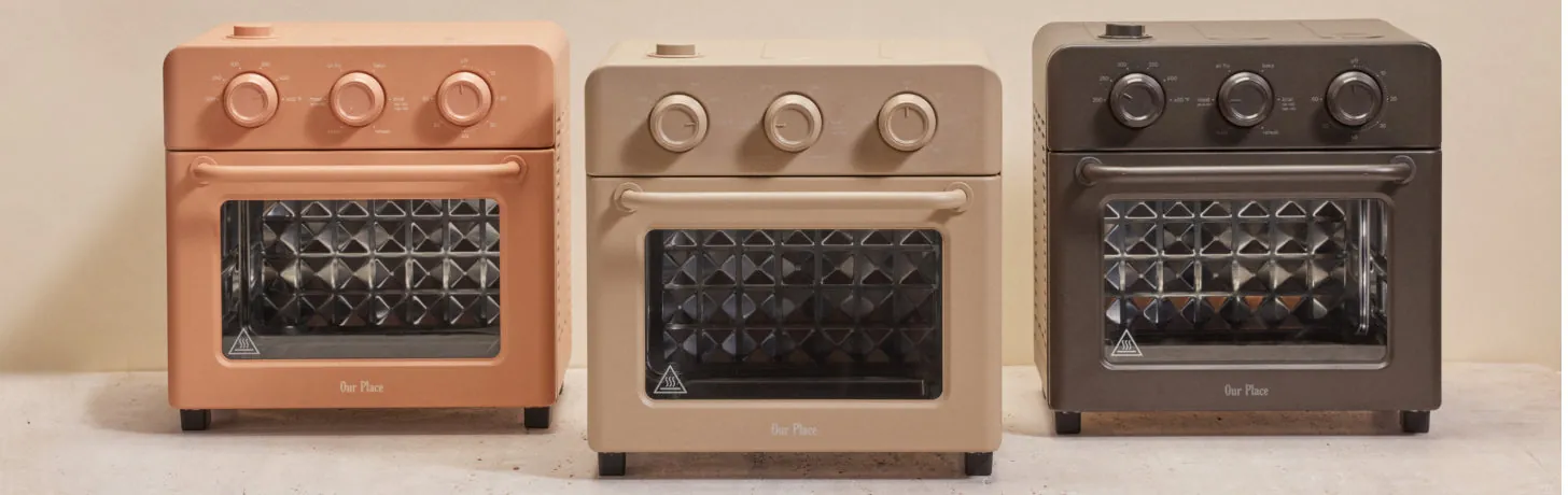 Hands adjusting dials on a Wonder Oven while roasted vegetables wait below